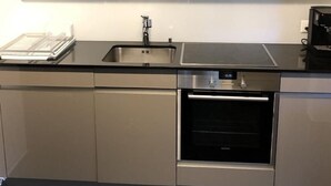 Et moderne køkken med stålemmer, indbygget ovn og vask.