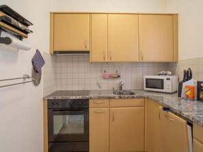 A kitchen with wooden cabinets, a microwave, a sink, and an oven. - Residenza Viramonte - Casa Cecilia, Wohnung 24 by Interhome (Vira)