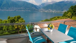 A terrace with a table and chairs overlooking a lake and mountains. - Residenza Viramonte - Casa Cecilia, Wohnung 24 by Interhome (Vira)