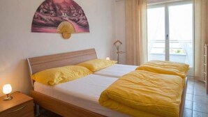 A hotel room with a bed, a nightstand, a wall-mounted fan, and a window with curtains. - Residenza Viramonte - Casa Cecilia, Wohnung 24 by Interhome (Vira)