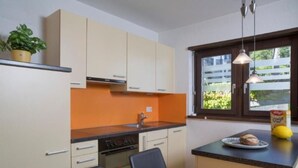 Una cocina compacta con comedor, que incluye horno empotrado, un lavamanos y un ventanal con vistas al exterior.