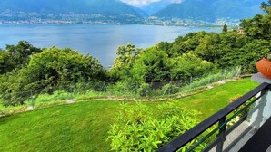 Un balcón con vista a un lago, montañas y una ciudad al fondo.