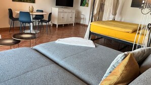 Ett modernt rum med en säng, ett skrivbord, en TV och en matplats.