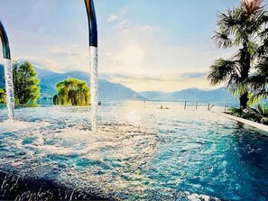 Una piscina con agua cristalina, rodeada de árboles y montañas al fondo.