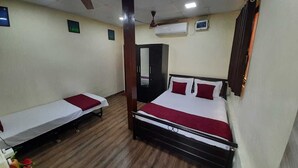 A hotel room with two single beds, a wooden floor, a ceiling fan, and an air conditioning unit. - MARS Resort (Shahapur)