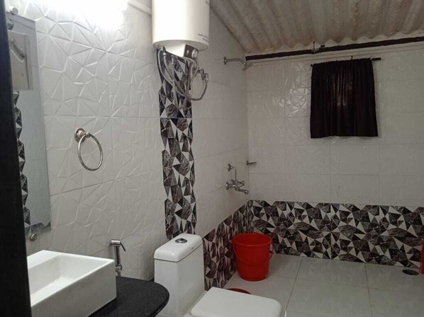 Une salle de bain avec un lavabo, des toilettes et une douche, le tout de couleur blanche.