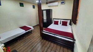 A room with two single beds and a larger bed, wooden flooring, and a ceiling fan. - MARS Resort (Shahapur)