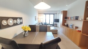 A modern living room with a dining area, a sofa, a TV, and a bookshelf. - Residenza Viramonte - Casa Aurelia, Wohnung 8 by Interhome (Vira)