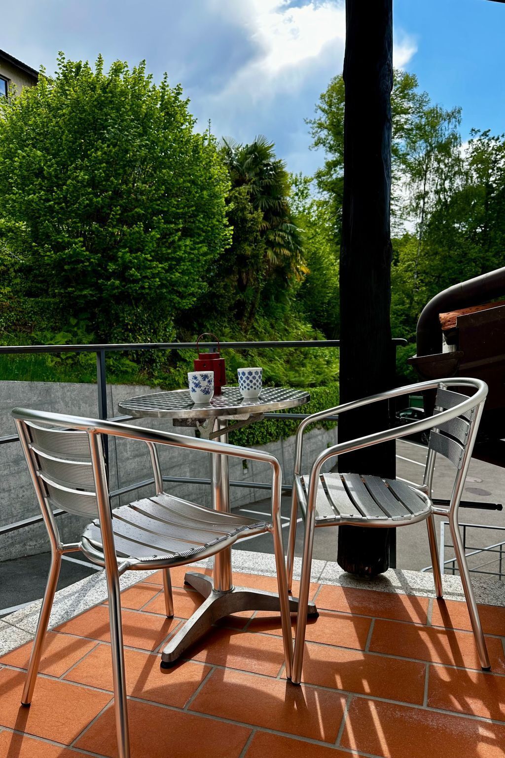 A patio with two metal chairs and a small round table, surrounded by a railing.