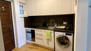 Een compacte keuken met een vaatwasser, wasmachine en een klein spoelgedeelte.