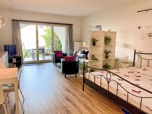 A bedroom with a bed, a desk, a chair, a sofa, a wardrobe, and a sliding glass door leading to an outdoor area. - Residenza Viramonte - Casa Daniela, Wohnung 31 by Interhome (Vira)
