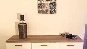 Een keukentablet met een houten blad, een metalen voorwerp erop, en een wand met ingelijste kunstwerken.