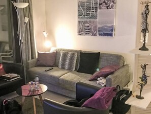 A living room with a sofa, a small table, a lamp, and a wall with framed pictures. - Residenza Viramonte - Casa Daniela, Wohnung 31 by Interhome (Vira)