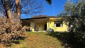 Una casa gialla con una scala in mattoni che conduce all'ingresso, circondata da alberi e da un'area verde.