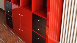 A red storage unit with multiple compartments and drawers against a wall. - Haus in Agno by Interhome (Agno)