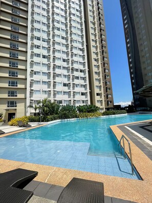 Una piscina con borde de baldosas, rodeada de edificios residenciales altos.