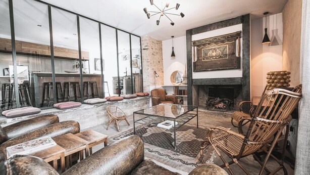 A modern living room with a glass partition, a fireplace, and a bar area in the background. - Gîte in the heart of the vineyards (Larroque)