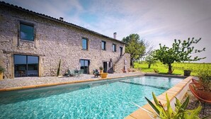 A stone building with a swimming pool, outdoor seating, and a vineyard in the background. - Gîte in the heart of the vineyards (Larroque)