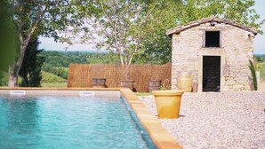 A swimming pool with a stone building in the background. - Gîte in the heart of the vineyards (Larroque)
