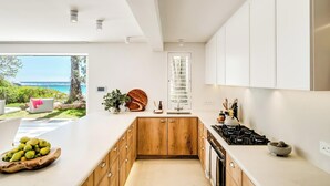 Una cucina moderna con mobili in legno, un'isola grande e vista sul mare.