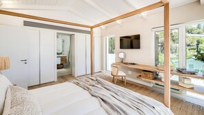 Una camera da letto con un letto, una scrivania e una TV. Si vede del verde attraverso la finestra.
