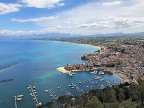 Un pueblo costero con un puerto deportivo, edificios históricos y una vista despejada del mar.