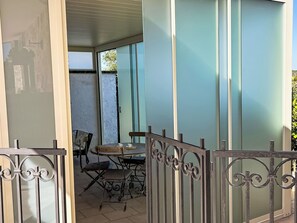 A balcony with a table and chairs, a metal gate, and a view of a building through the glass wall. - Neuer fabelhafter Trullo mit privatem Pool by Interhome (Martina Franca)