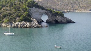 Eine Küstenlandschaft mit einer natürlichen Felsformation, ruhigem Wasser und Booten.