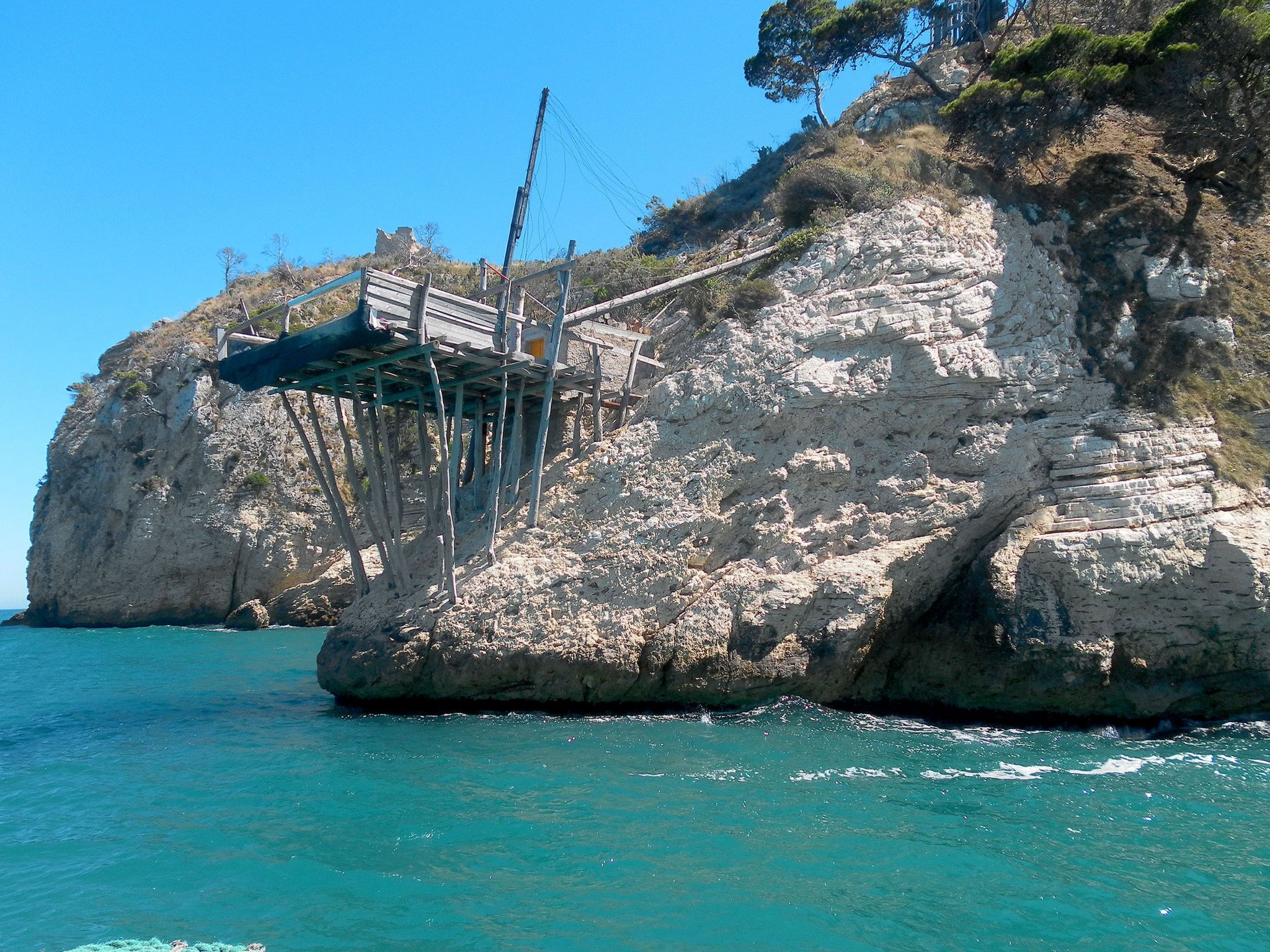 Formación rocosa en la costa con un puente de madera que conduce a una pequeña plataforma.