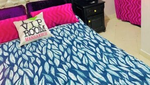 Un dormitorio con cama, mesita de noche, cajón y cortina.