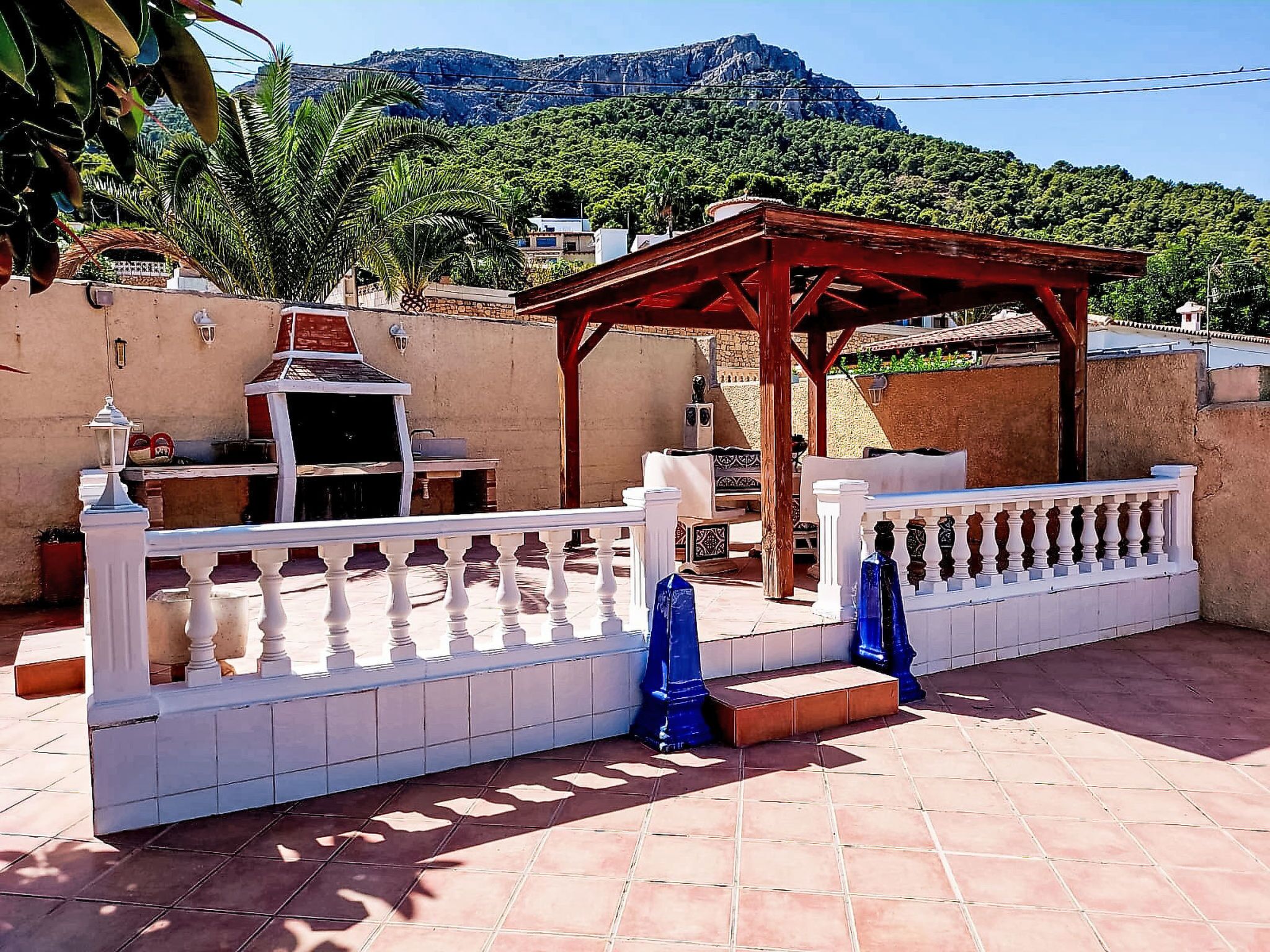 Eine Terrasse mit Grill, einer Pergola und Bergblick.