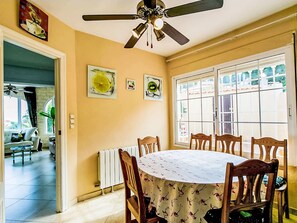 A dining area with a ceiling fan, a round table with chairs, and artwork on the walls. - Casa Flamingo by Interhome (Calpe/Calp)