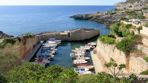 Un port de plaisance situé sur la côte, avec des bateaux amarrés, des falaises rocheuses et une vue dégagée sur la mer.