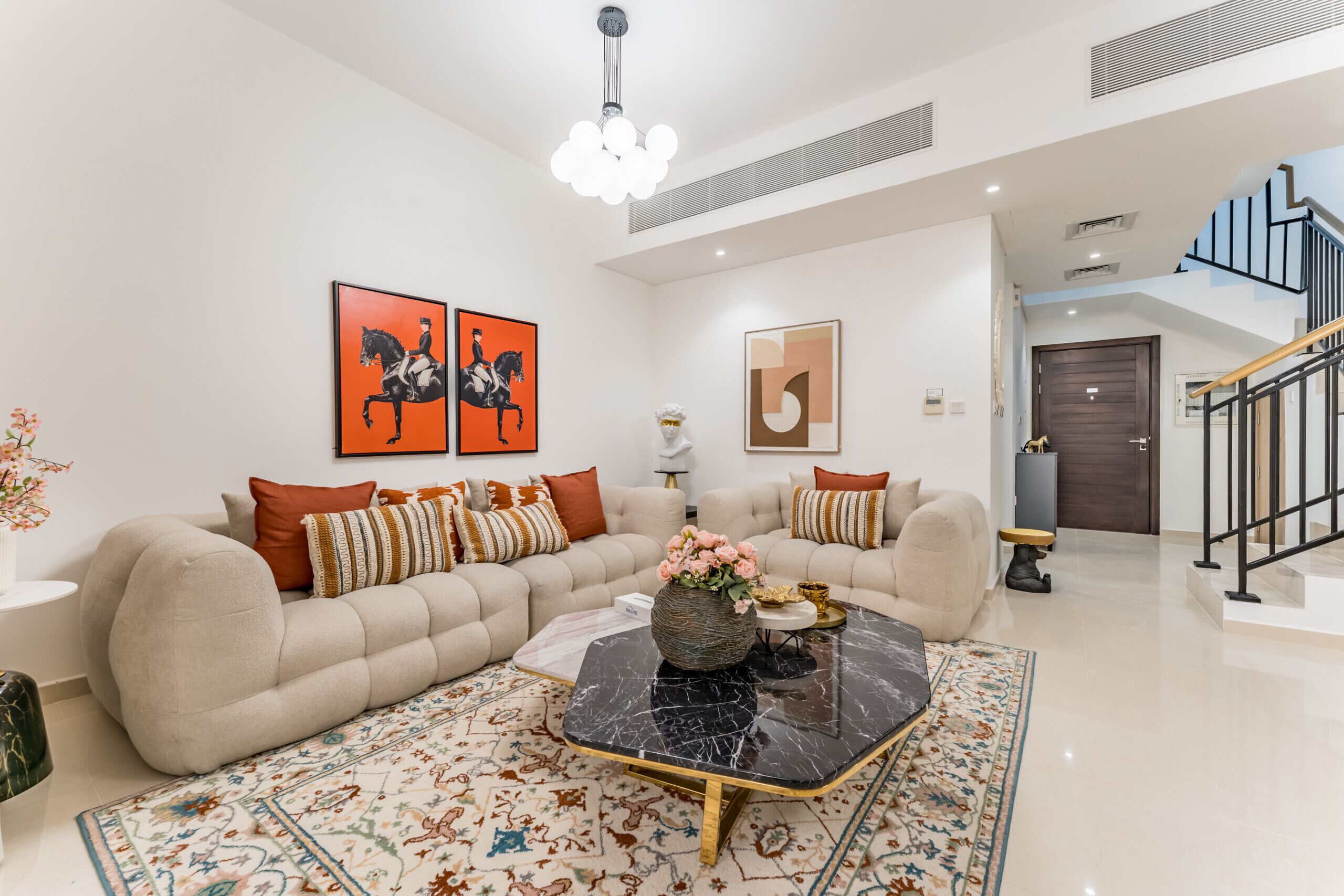 A modern living room with a sectional sofa, a black marble coffee table, and a patterned rug.