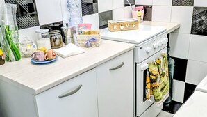 Una cocina con armarios blancos, una estufa y diversos utensilios sobre la encimera.