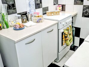 A kitchen with white cabinets, a stove, and various kitchen items on the counter. - Giotto Aradeo by Interhome (Acquarica del Capo)