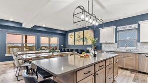 A modern kitchen with a large island, white cabinets, and a view of the outdoors.