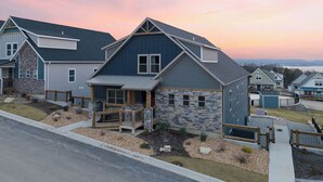 Un moderno edificio residencial con fachada de piedra, un amplio porche delantero y un garaje.