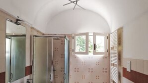 Un bagno con uno specchio grande, un lavandino, una doccia e una finestra.