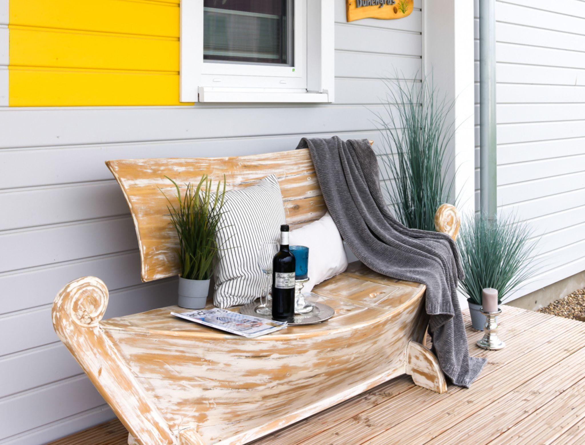 Un banc en bois sur lequel sont posés une bouteille de vin, un verre et une bougie.
