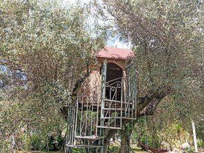 A treehouse structure with a metal railing and a red roof, surrounded by dense foliage. - Residenz Heaven 41R by Interhome (Capo Vaticano)
