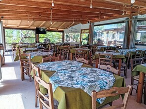 A restaurant with wooden tables and chairs, large windows, and a wooden ceiling. - Residenz Heaven 41R by Interhome (Capo Vaticano)