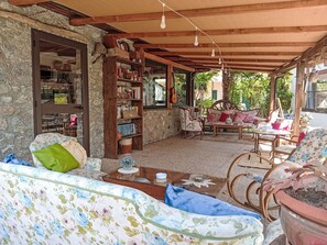 Un cuarto acogedor y rústico con techo de madera, una estantería, un sofá con tapicería floral y un comedor con mesa y sillas.