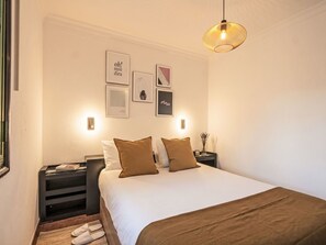 Ein Schlafzimmer mit einem Bett, Nachttischen, einer Hängelampe und gerahmten Bildern an der Wand.