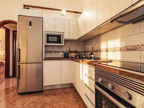 Eine Küche mit Kühlschrank, Mikrowelle, Backofen und einer Holzausziehtheke.