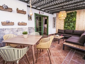 Eine Terrasse mit Esstisch, Stühlen, einer Couch und einer Hängeleuchte.