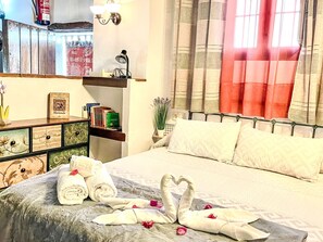 A neatly arranged bedroom with a bed, pillows, a bedside table, a shelf with books, and a window with curtains. - Schöne Ferienwohnung in Iznájar mit Garten, Terrasse und Grill by Interhome (Fuentes de Cesna)