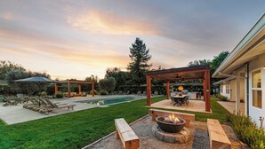 A backyard with a pool, outdoor seating, and a fire pit.