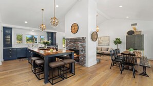 A spacious kitchen with a central island, dark blue cabinets, and a brick fireplace.