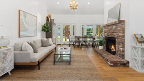 A spacious living room with a fireplace, a sofa, a coffee table, and a dining area with chairs.